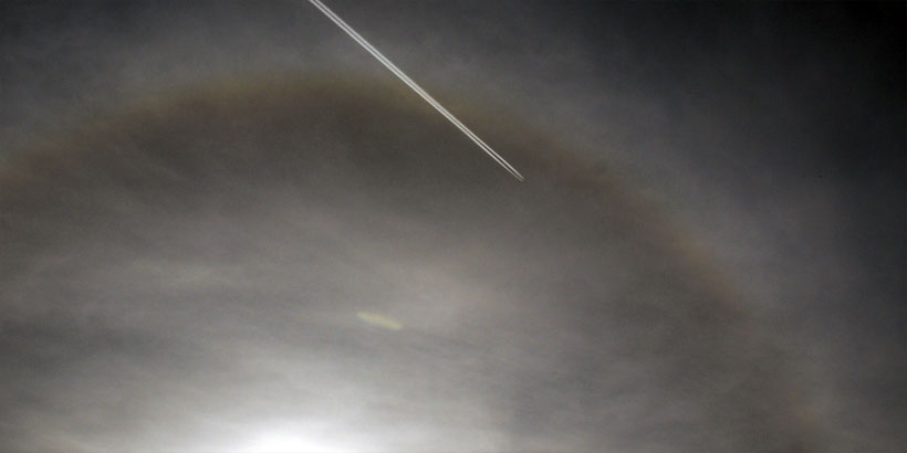 Cigar-shaped UFO and airplane in Sun halo